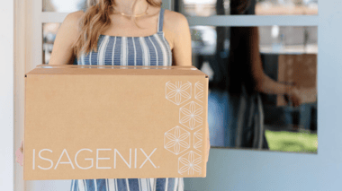Woman holding an Isagenix delivery box at her front door.