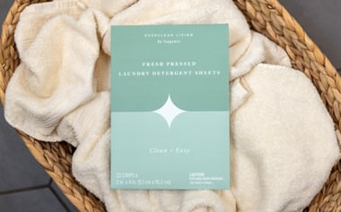 Everclean Living laundry detergent sheets package on folded towels in a woven basket