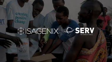 Indoor community scene showing several people gathered around an open cardboard box containing SERV food packages, with overlaid logos reading ‘ISAGENIX’ and ‘SERV International’ centered across the image.