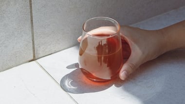 Hand holding a glass of light Ionix Supreme by a tiled surface.
