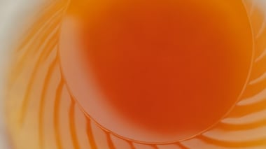 Close-up of an orange liquid with soft swirling patterns.