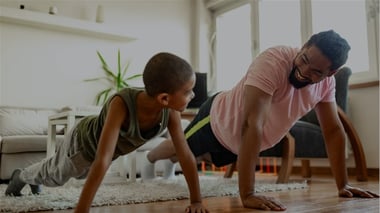 Video thumbnail showing an adult and a child performing plank exercises on a floor in a living room.
