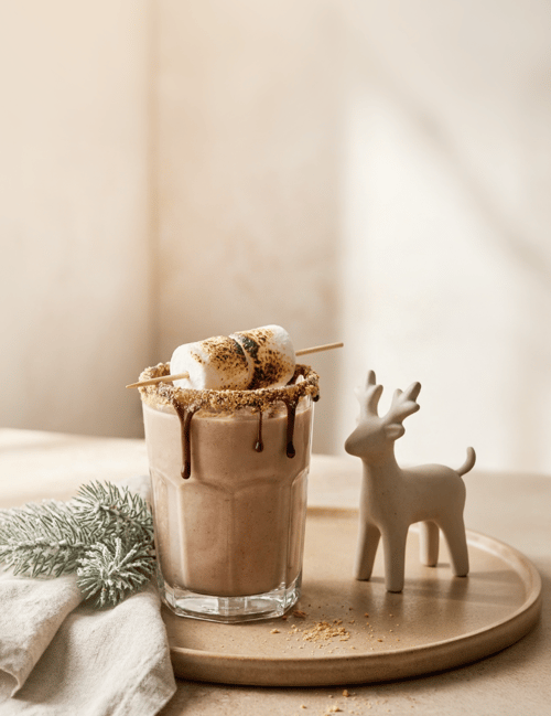 Banana cream shake garnished with a caramelized banana slice, surrounded by holiday décor.