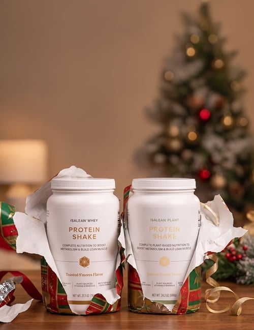 IsaLean Whey Toasted S’mores and IsaLean Plant Banana Cream protein shakes displayed with holiday gift wrap.